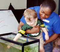 A student helps a young visitor explore a seagrass tank